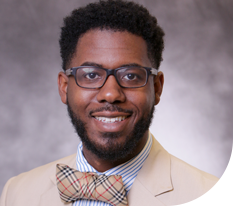 African American man with beard, bow tie and light suit smiling at camera