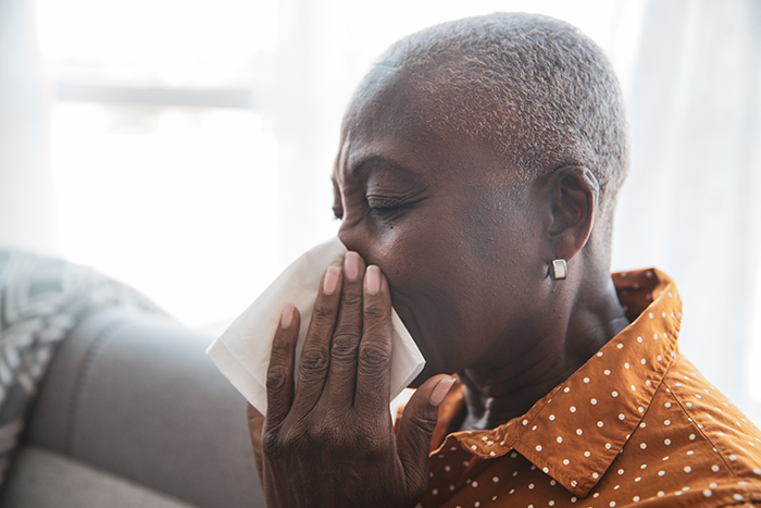African American woman coughing and sitting on couch