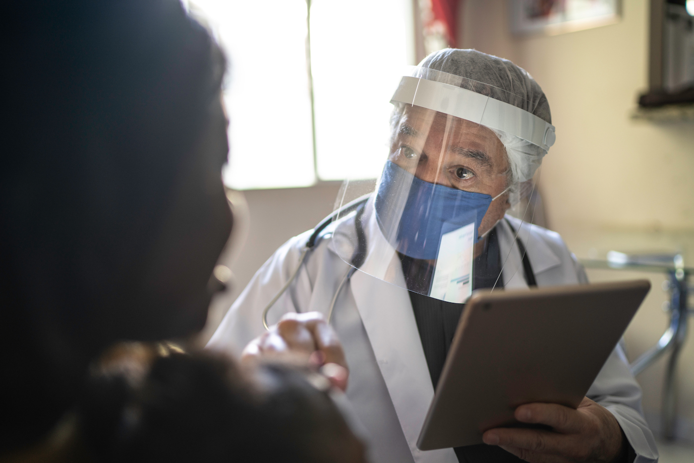 Doctor wearing protective face mask on medical consultation at patient home