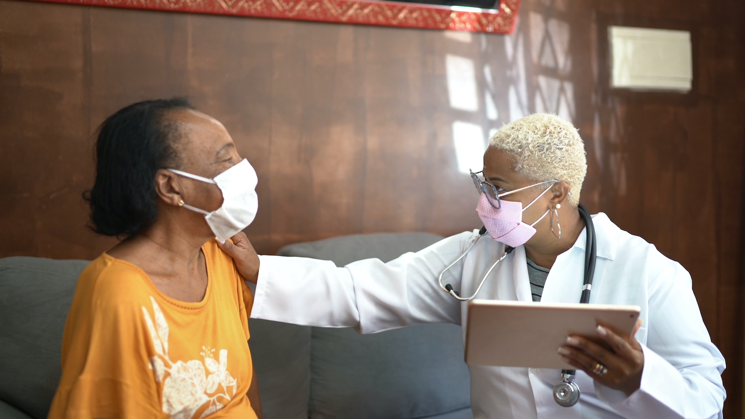 Doctor talking to senior female patient while being in a home visit