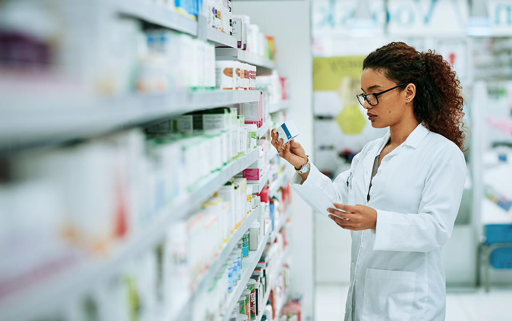 female pharmacist reading medicine box on shelf