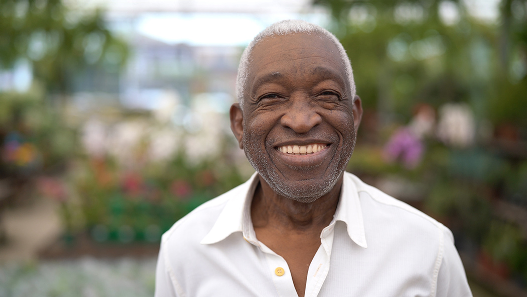 Smiling older man with garden blurred in background